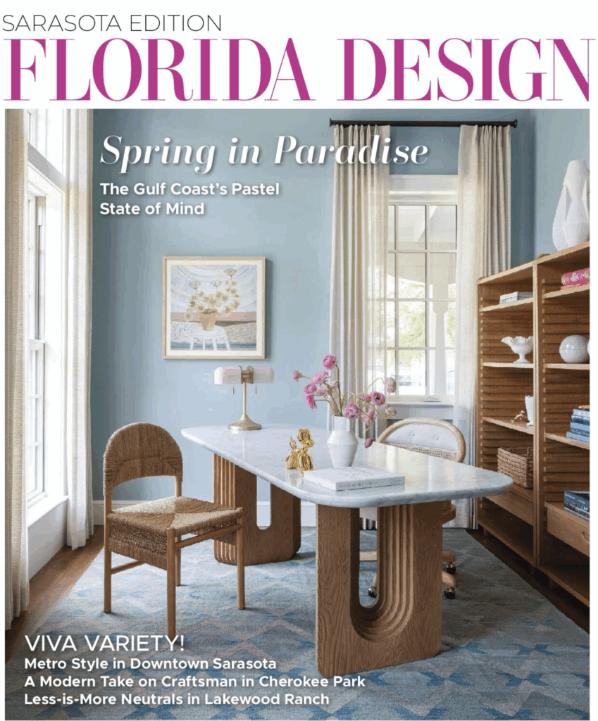 Cover of Florida Design magazine's Spring 2025 issue depicting a stylish room with a blue wall, marble table, wicker chair, and shelves.